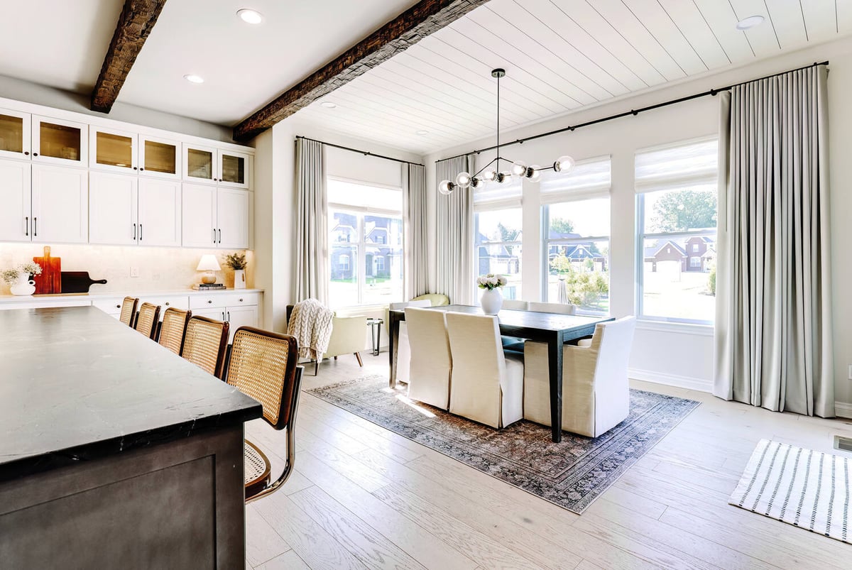 Open dining area with natural light and wood ceiling beams by Cabinet Creations in Bloomfield Hills, MI