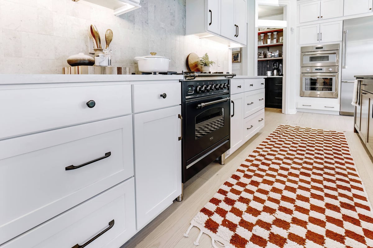 Custom kitchen with checkerboard rug and white shaker cabinets by Cabinet Creations in Oakland County, MI