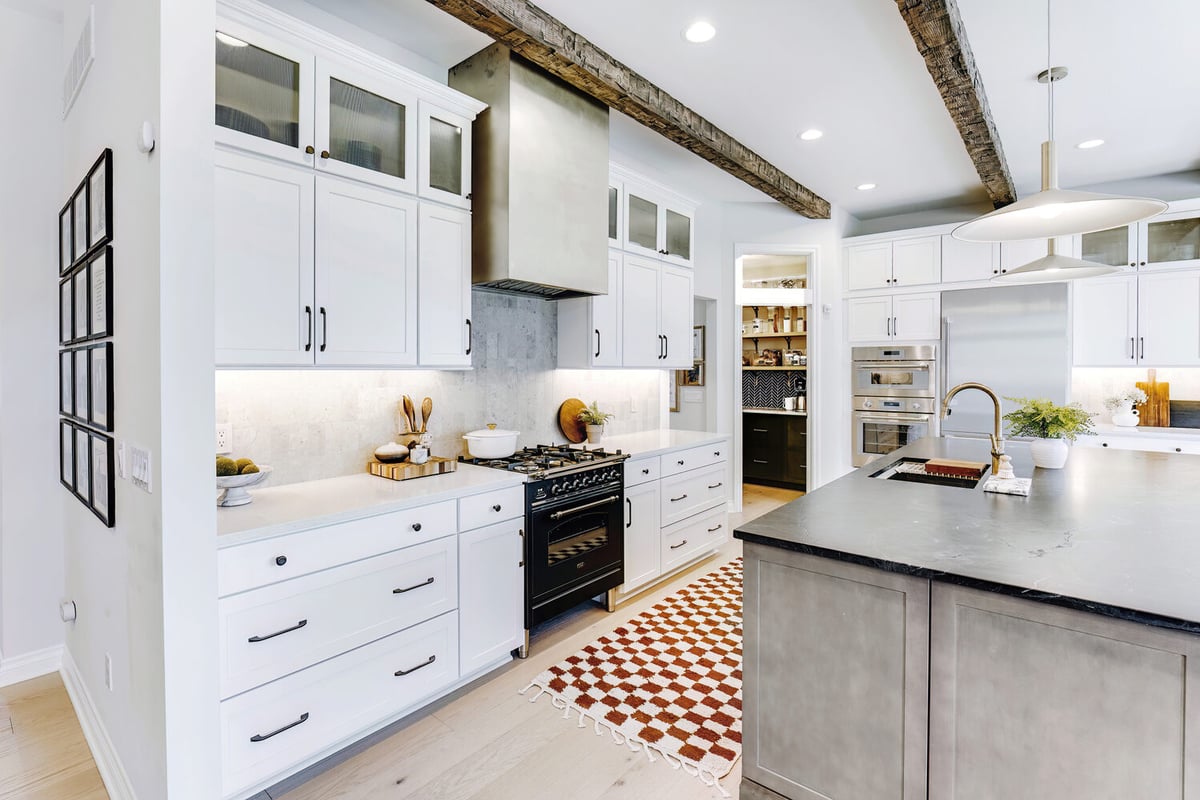 White and stainless kitchen design with gas stove and vent hood by Cabinet Creations in Birmingham, MI
