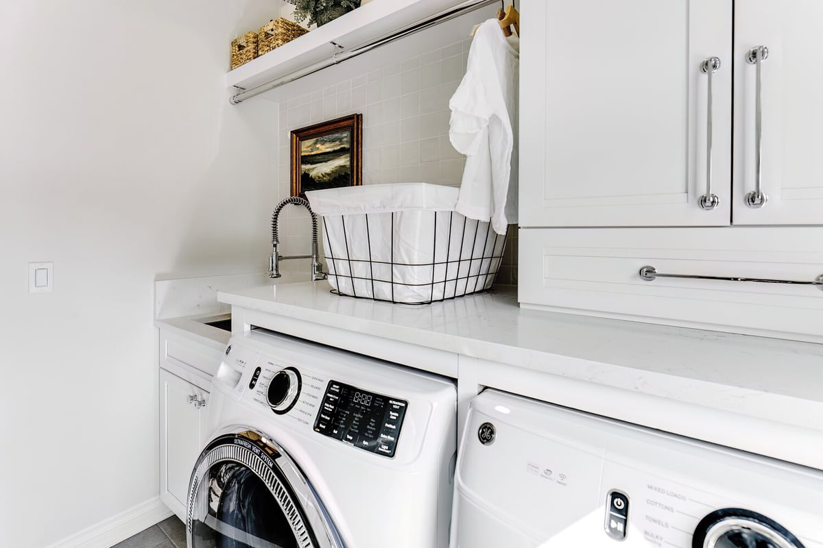 Side view of custom laundry room with washer and dryer under quartz countertop by Cabinet Creations in Oakland County, MI