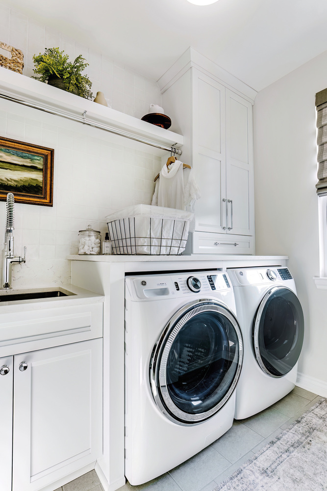 Vertical view of custom laundry room with modern appliances and white tile by Cabinet Creations in Oakland County, MI