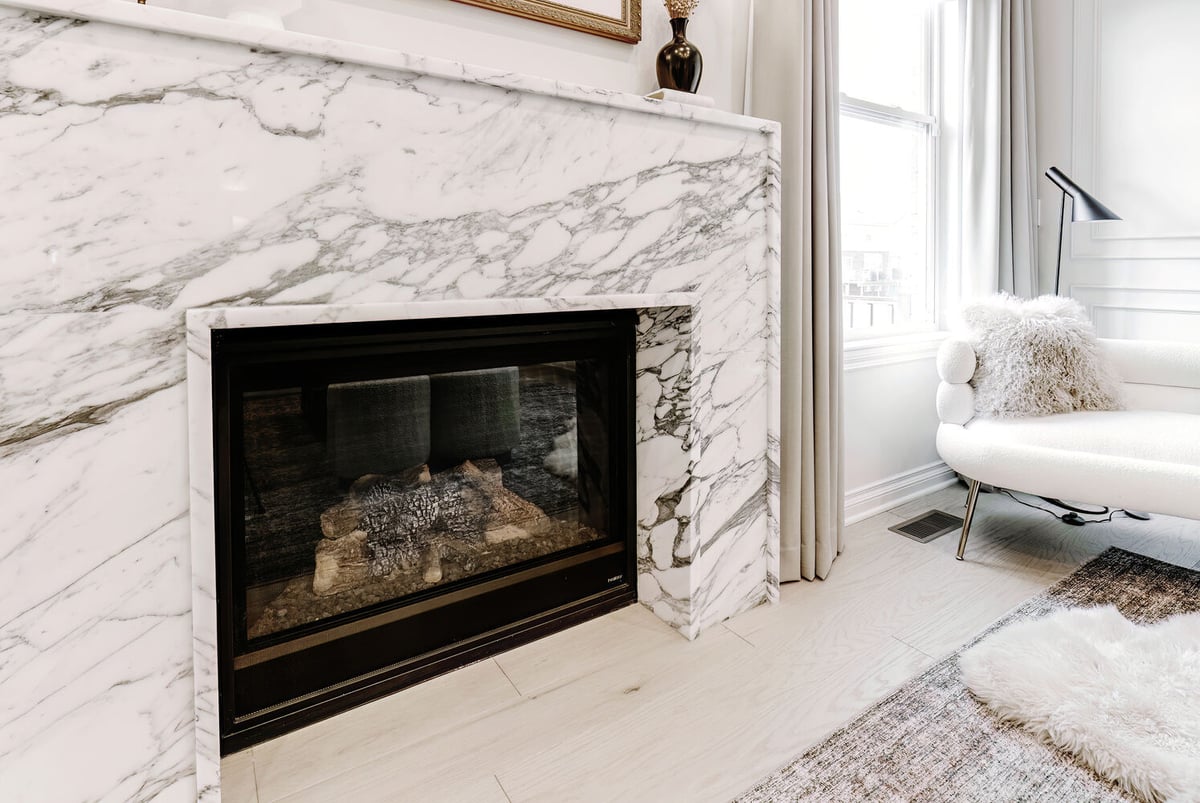 Fireplace with polished marble surround next to a cozy sitting area by Cabinet Creations in Oakland County, MI