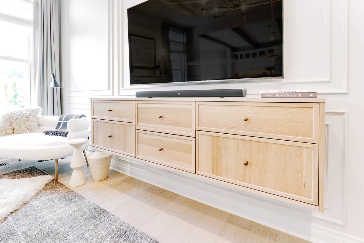 Light oak floating console with mounted TV in custom living room by Cabinet Creations in Oakland County, MI