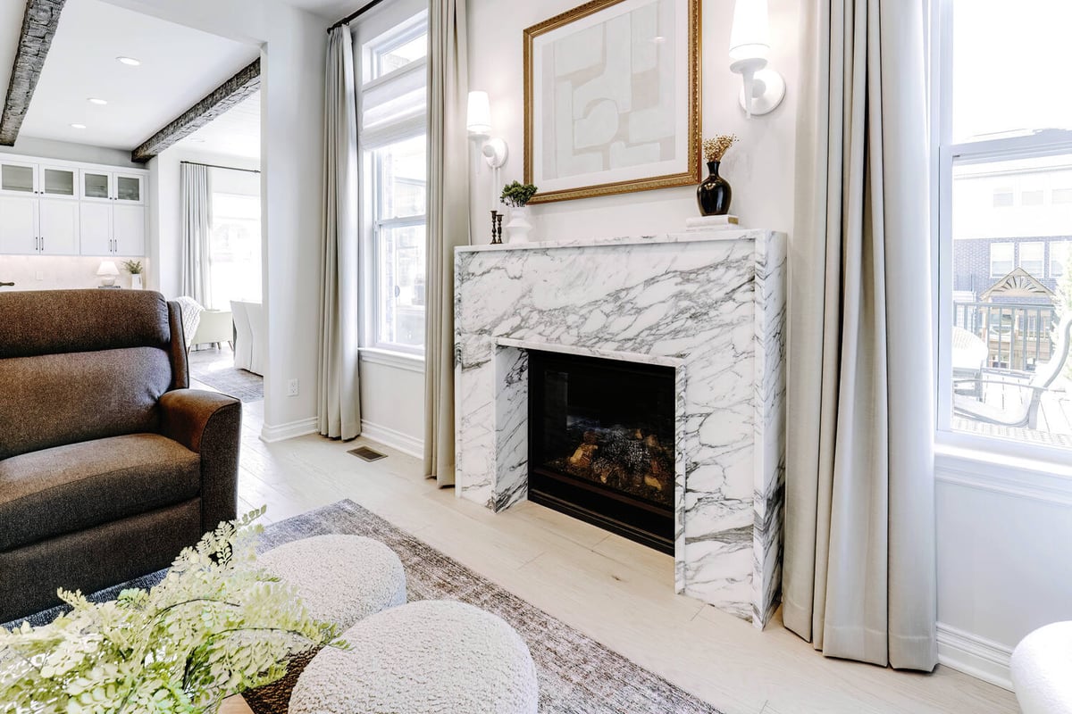 Side view of marble fireplace with decorative wall sconces in living room by Cabinet Creations in Oakland County, MI