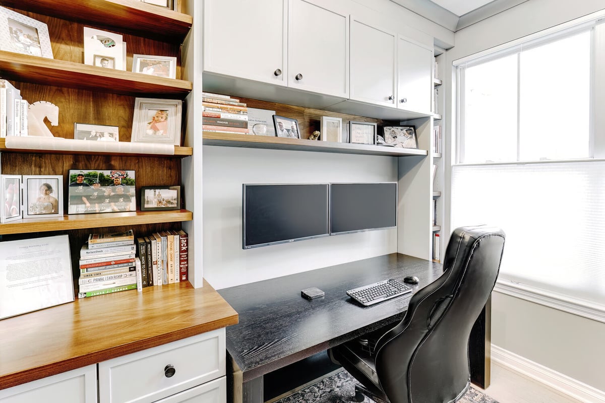 Close-up of open shelving with framed photos and books in a Waterford Township office by Cabinet Creations