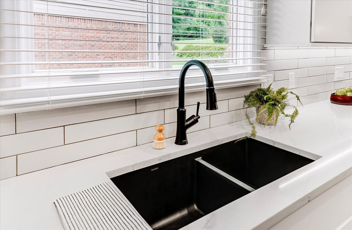 Black double sink and faucet with large kitchen window in a Michigan custom home by Cabinet Creations