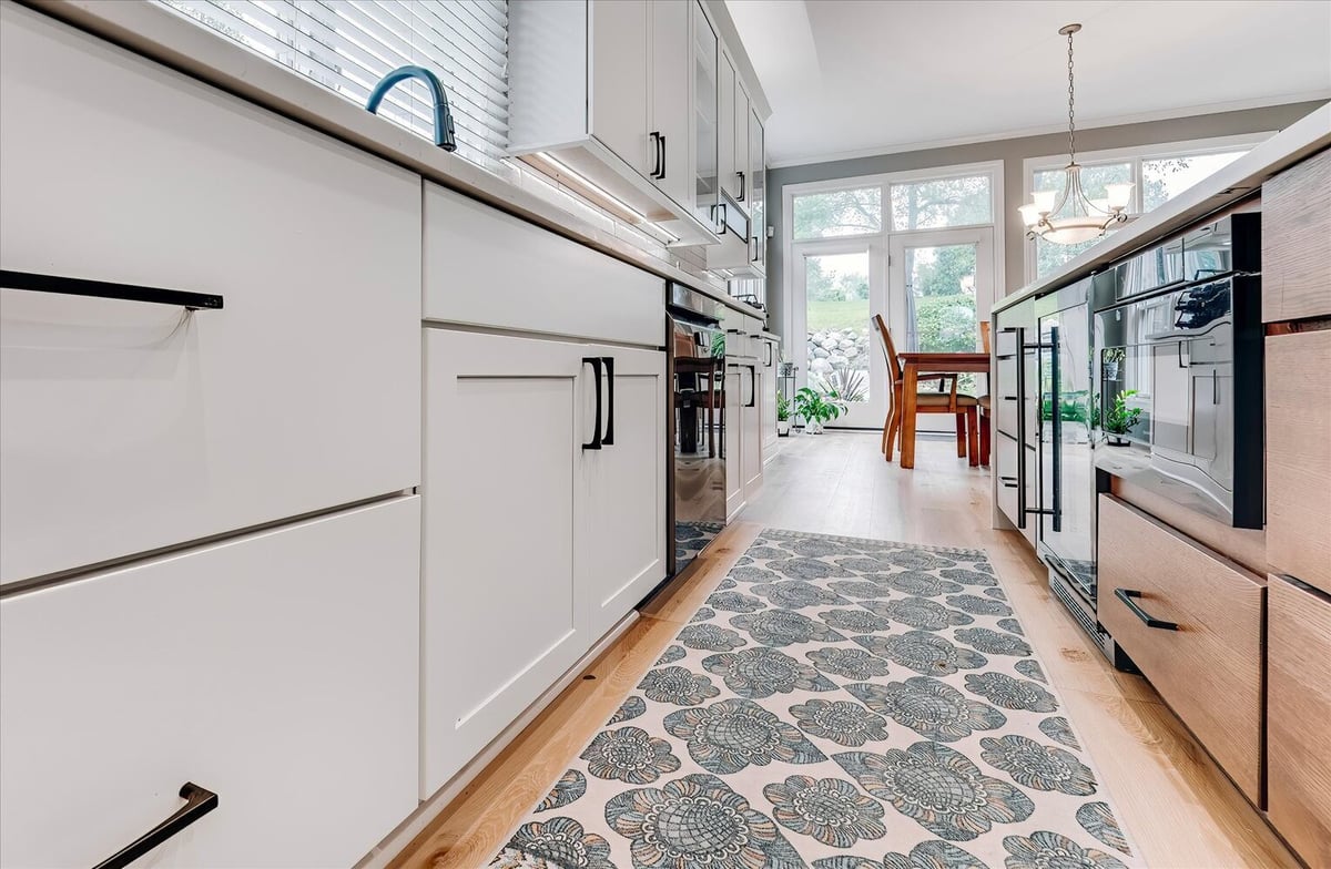 Close-up of custom white cabinetry and floral runner in kitchen remodel by Cabinet Creations