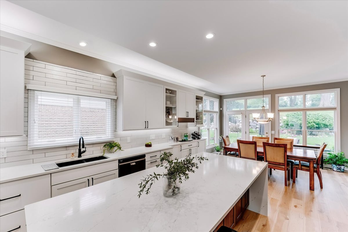 Dining area adjacent to custom kitchen with full-height windows by Cabinet Creations in Michigan