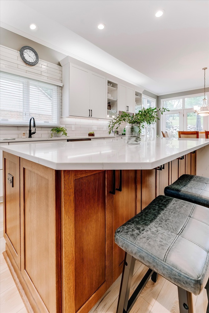 Elegant kitchen design featuring wood-paneled island and open seating by Cabinet Creations, Oakland County