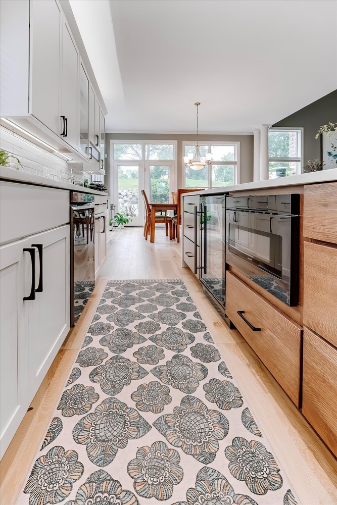 Hallway view of a modern custom kitchen with beverage fridge and dining space by Cabinet Creations
