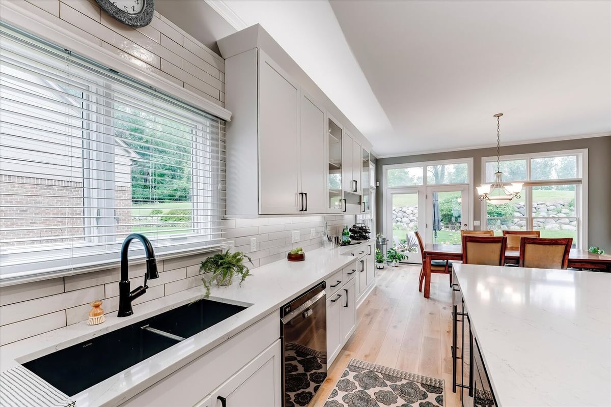 Kitchen and dining area with full-height windows and white cabinetry in a Michigan custom home by Cabinet Creations