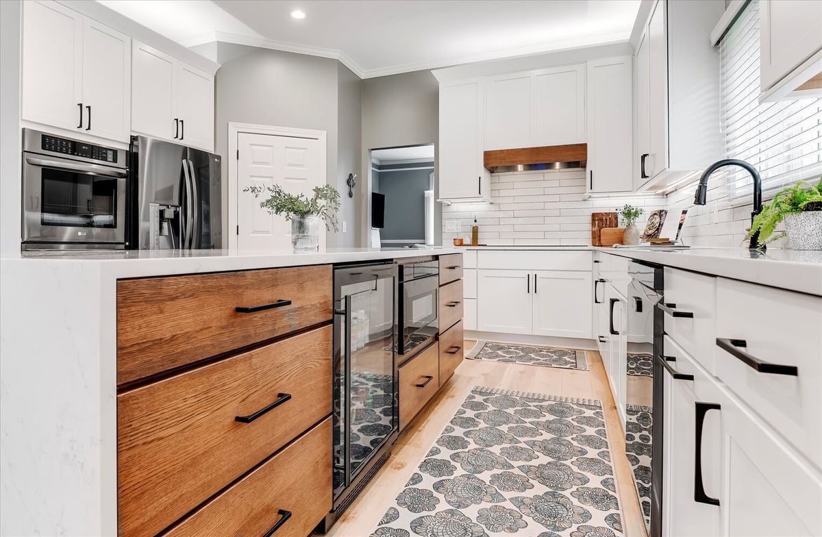 Long view of a custom kitchen island with beverage cooler and wood cabinetry by Cabinet Creations