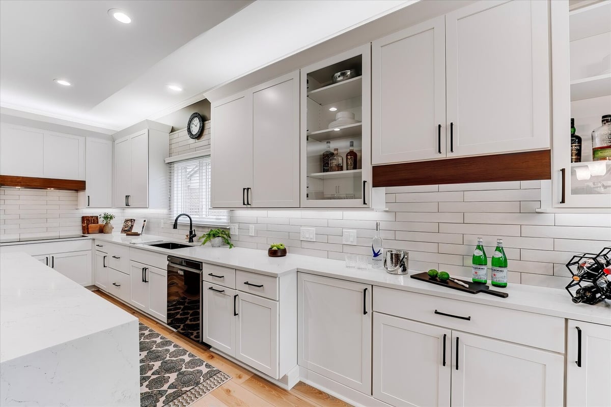 Sleek custom kitchen with white cabinetry and tile backsplash in a Michigan home by Cabinet Creations