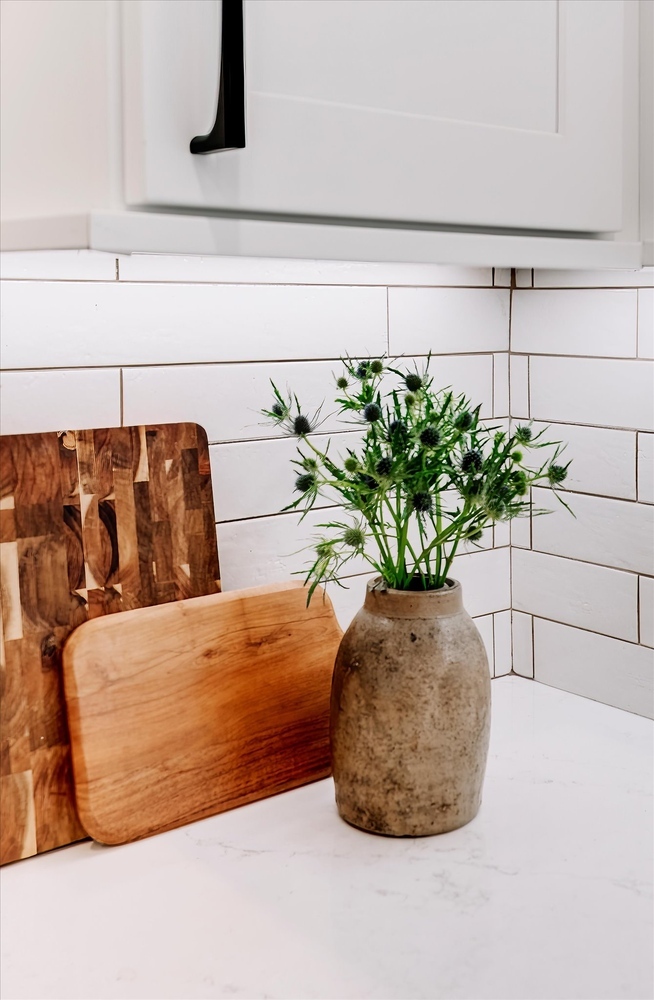 Stone vase with greenery and wood cutting boards on quartz counter in a Cabinet Creations kitchen