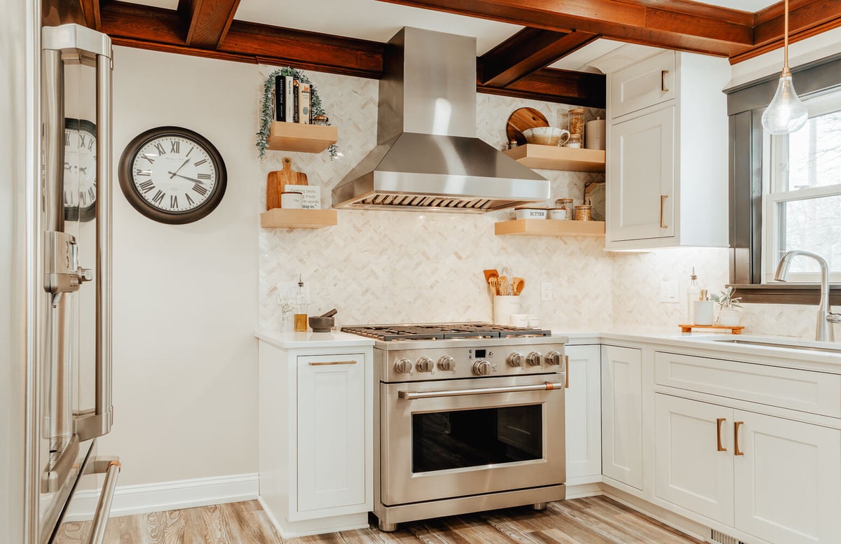Stainless steel range and vent hood with wood beam ceiling accents by Cabinet Creations in Lake Orion, MI