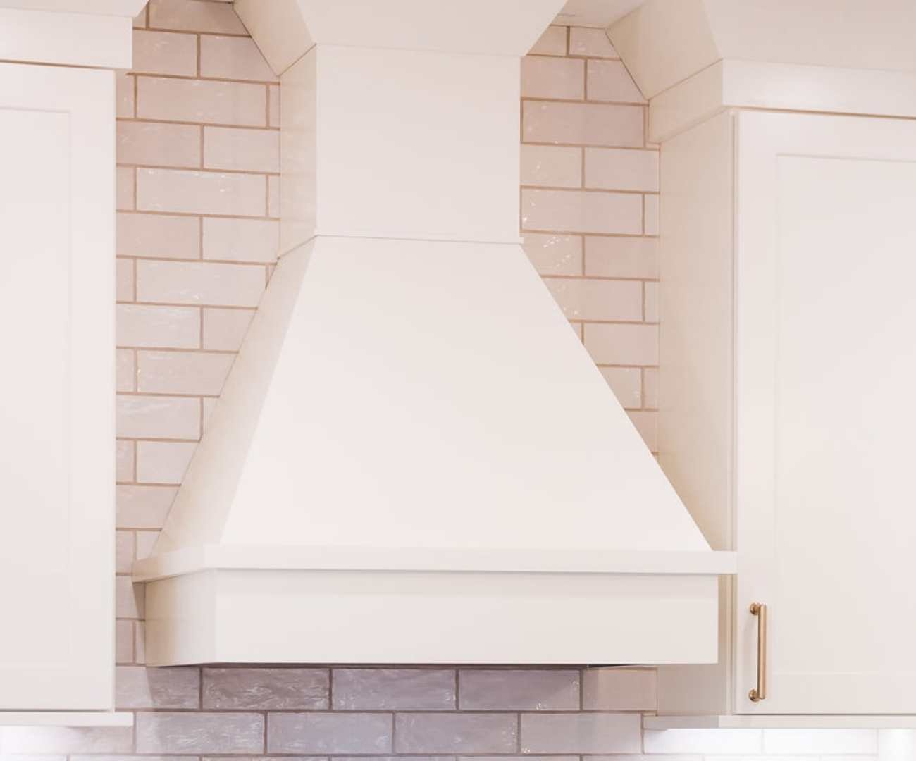 Close-up of custom white range hood and tile backsplash by Cabinet Creations in Bloomfield Hills, MI Close-up of custom white range hood and tile backsplash by Cabinet Creations in Bloomfield Hills, MI
