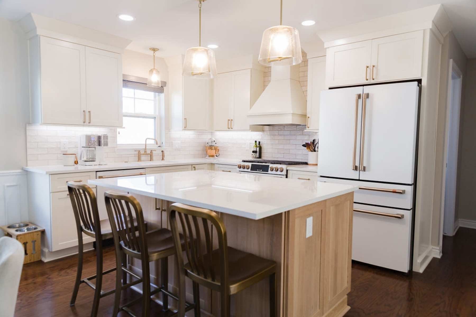 Custom white kitchen with modern vent hood and brass accents by Cabinet Creations in Oakland County, MI