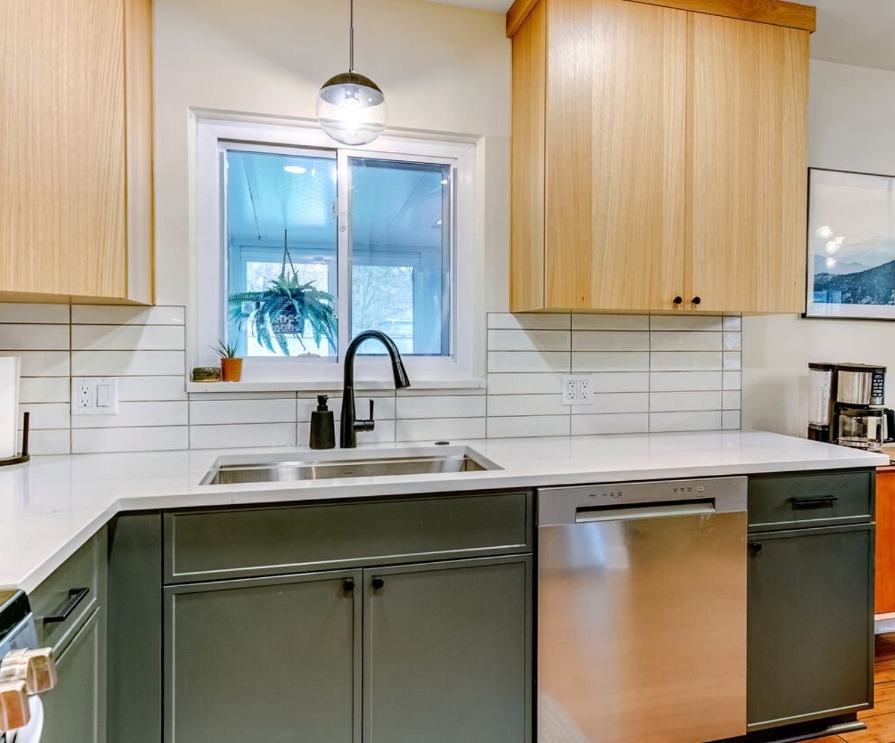 Custom kitchen sink area with large window and natural wood cabinetry in Clarkston, MI by Cabinet Creations