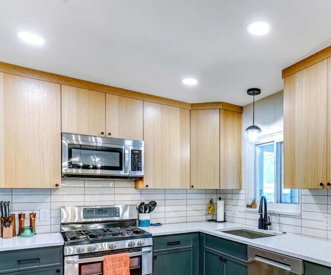 Custom kitchen with layered lighting, clean lines, light wood cabinets, and white countertops by Cabinet Creations in Clarkston, MI