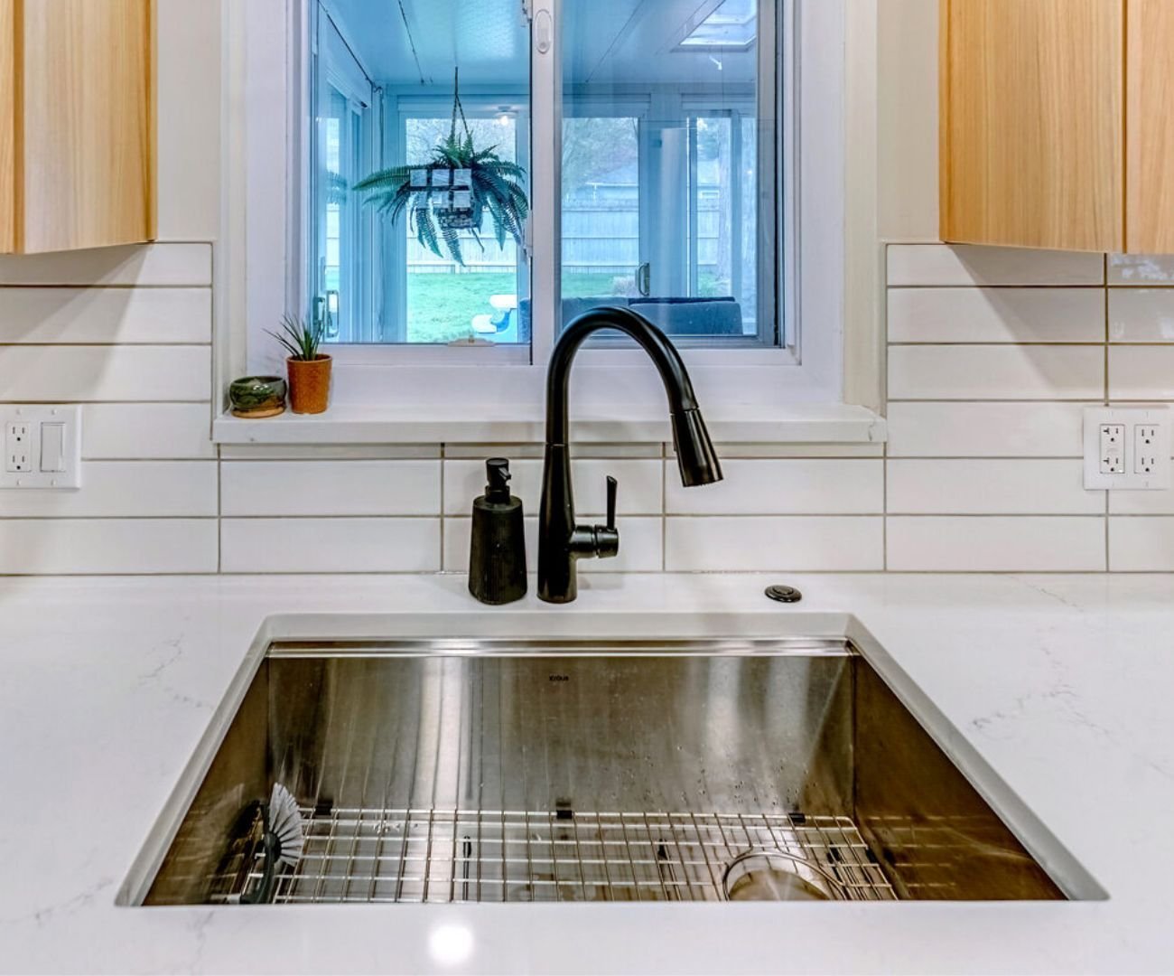 Oakland County custom kitchen with a black faucet, clean backsplash lines, and dual outlet setup by Cabinet Creations