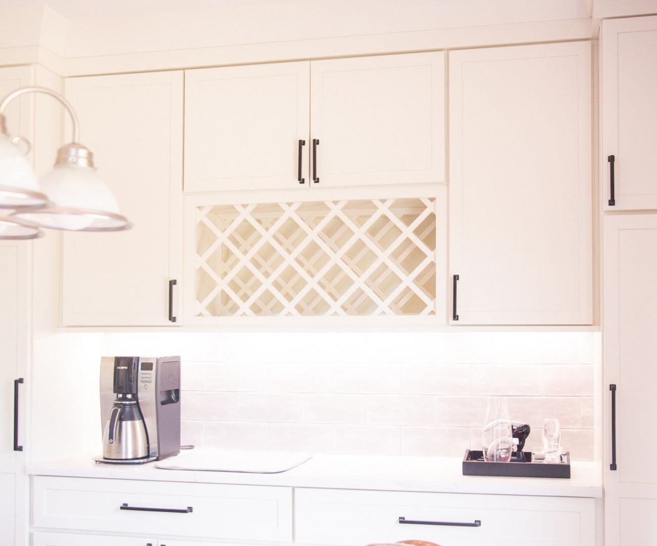 Elegant kitchen design with white cabinetry, wine storage, and subtle under-cabinet lighting by Cabinet Creations in Oakland County, MI