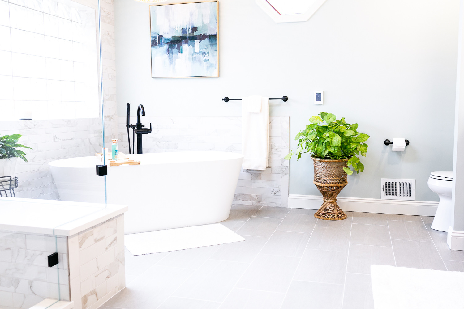 Bright modern bathroom by Cabinet Creations in White Lake, MI featuring a freestanding tub and light tile flooring