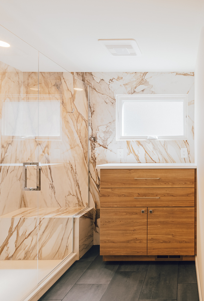 Luxury custom home bathroom with wood vanity and marble shower by Cabinet Creations in Birmingham, MI