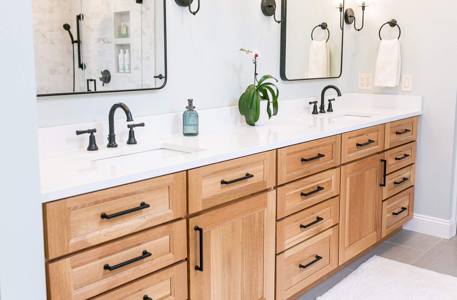 Stylish bathroom remodel with light wood cabinetry and matte black hardware by Cabinet Creations in White Lake, MI