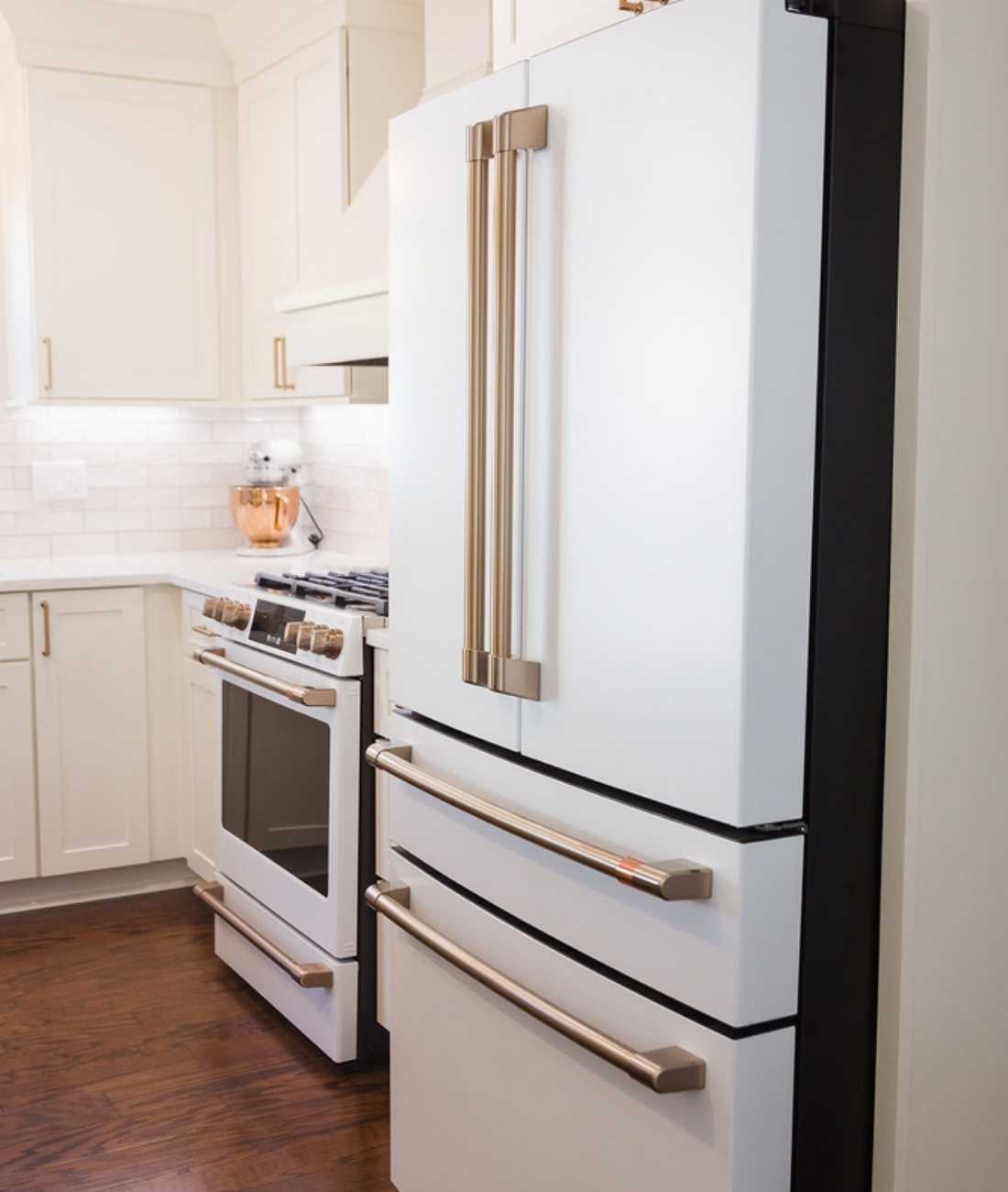 Modern white refrigerator and cabinetry with brass hardware by Cabinet Creations in Ferndale, MI