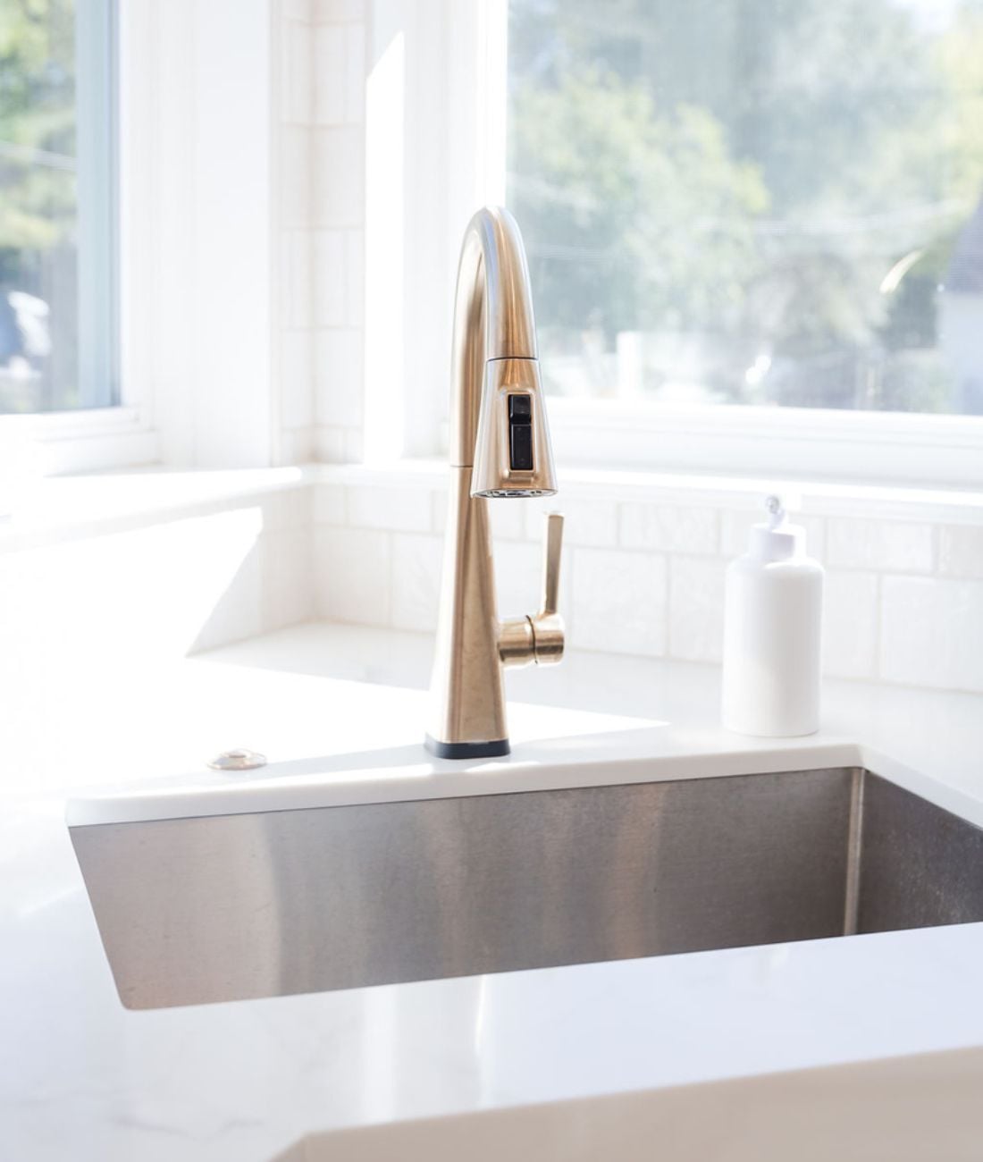 Brushed gold kitchen faucet over stainless sink designed by Cabinet Creations in White Lake Township, MI